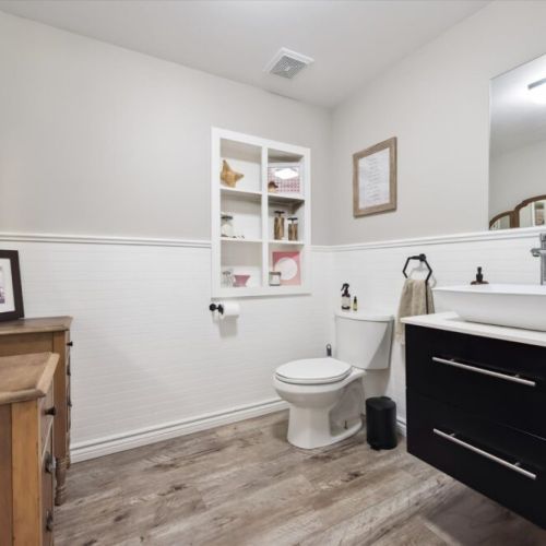Modern full bathroom with stylish vanity, shelving, and plenty of space for guests.