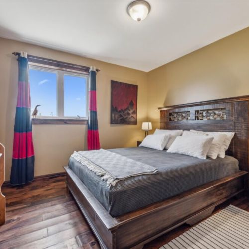 Warm and comfortable main-level bedroom with a queen bed and handcrafted headboard.