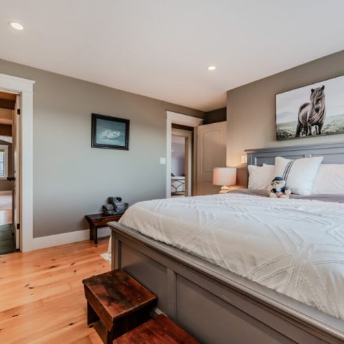 A charming bedroom with a comfortable bed, rustic wooden steps, and thoughtful decor, creating a cozy and relaxing atmosphere. The space is illuminated by natural light, with soft neutral tones enhancing the peaceful ambiance.