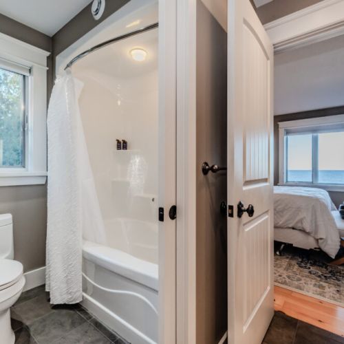 A clean and modern bathroom with a window providing a serene view of nature, along with a well-equipped shower area.