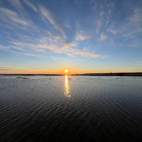 Enjoy breathtaking sunsets over calm waters, with the sky painted in shades of orange and blue, viewed right from Silver Birch Cottage.