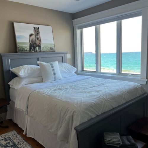 Cozy bedroom with a serene lake view, featuring a comfortable bed and soft, neutral decor—perfect for a peaceful retreat. (Queen Bed)