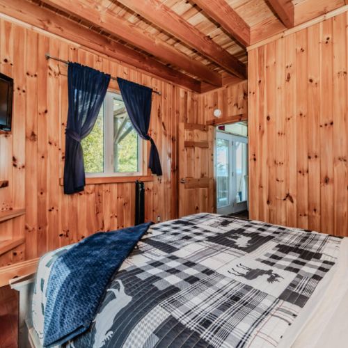 Inviting queen bedroom with wood beams, plush bedding, and outdoor access—perfect for restful nights after a day on the trails or beach.