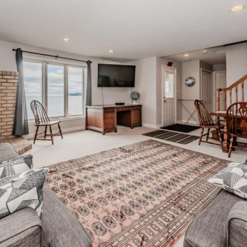 This bright and comfortable family room provides ample seating, a wood-burning stove, and easy access to the outdoor area, perfect for cozy evenings after a day on the bay.