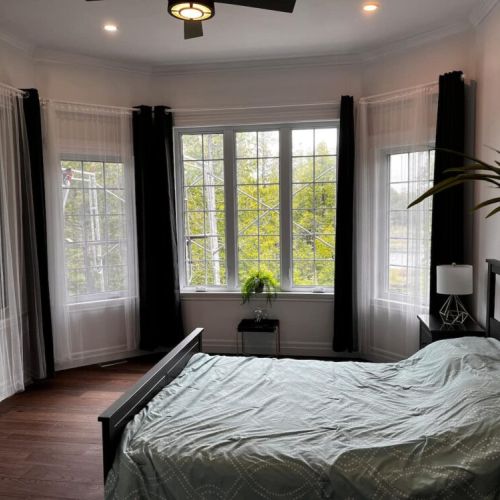 Spacious primary bedroom with king bed, bay windows, and plenty of natural light