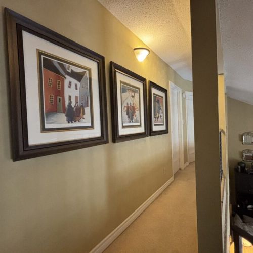 Hallway Gallery: Stroll through the upstairs hallway of The Louise, lined with framed art that adds a cultural touch to the space. These prints provide guests with visual stories, creating a personal gallery experience as they move between the cozy comforts of the cottage's rooms.