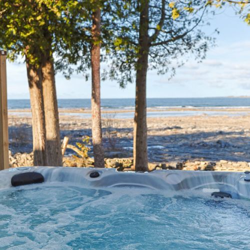 A soak with a view: Settle into the bubbling water and look out across the rocky shoreline to the lake, framed by waterfront trees.