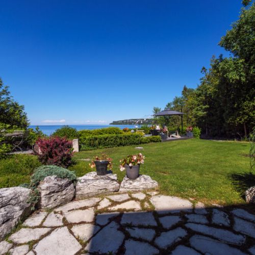 Beautiful stone pathways wind through manicured gardens toward spectacular Georgian Bay views.