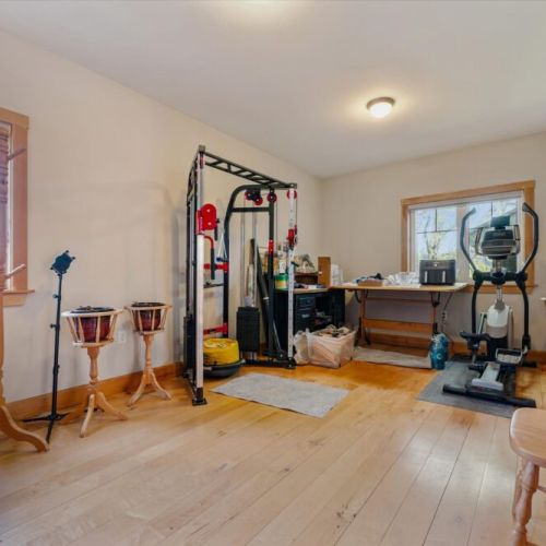Open loft area with workspace, fitness equipment, and soaring wood ceilings.