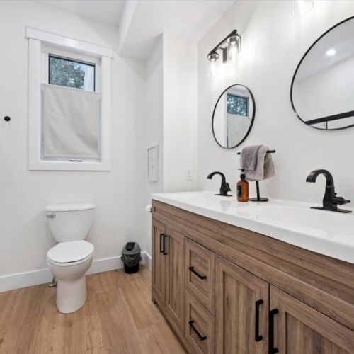 Modern full bathroom with double vanity, sleek fixtures, and bright natural light.